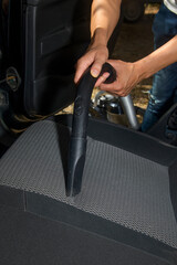 a man vacuuming the seat of a car