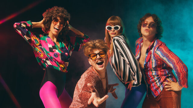 Glam retro group expressing charisma with colorful disco outfits. Concept of 70s inspired fashion, pop culture events, nostalgia lifestyle and vibrant party identity