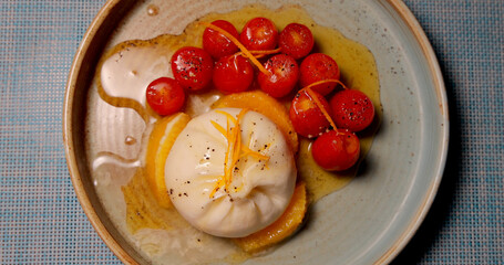 Burrata and cherry tomatoes on rustic ceramic plate. Italian cuisine, cheese, fresh, vibrant,...