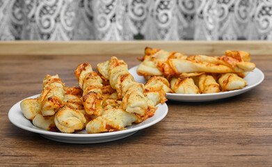 Party snack: pizza-flavored puff pastry sticks with ham and cheese