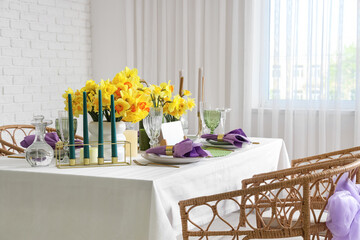 Beautiful table setting with daffodils and candles for wedding celebration in room