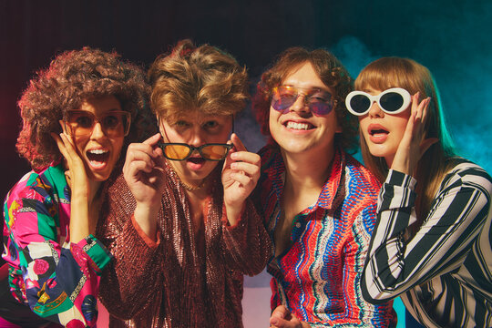 Smiling retro group in bold disco costumes celebrating friendship. Concept of vintage style, nostalgic pop culture campaigns, lifestyle promotion and joy of expressive togetherness.