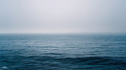 Obraz premium misty horizon over calm ocean with blue and gray water tones 
