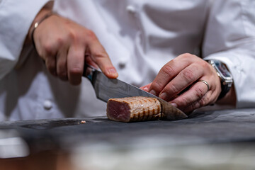 Chef étoilé en train de découper soigneusement la viande pour un plat gastronomique en cuisine professionnelle.