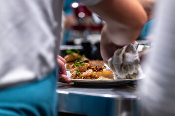 Main d’un chef étoilé en pleine préparation culinaire, dressant un plat gastronomique avec précision.