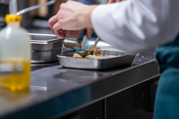 Main d’un chef étoilé en pleine préparation culinaire, dressant un plat gastronomique avec précision.