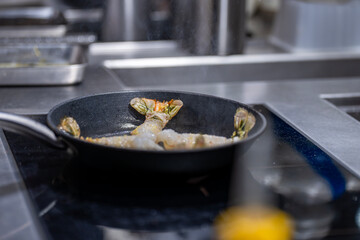 Langoustines disposées dans une poêle en pleine cuisson, dégageant une ambiance culinaire raffinée.