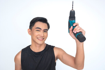 A lively young Asian man holding up his wireless drill with a bright smile, showcasing his skillful...