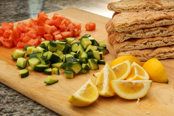 Cutting Board with Chopped Cucumber, Tomatoes, Lemon, and Pita Bread