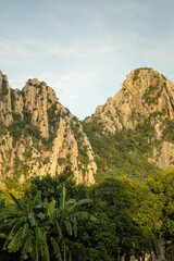 The sun's golden light streams down on the mountains in the middle of rice fields in the evening.