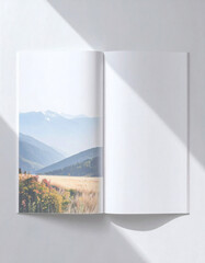 An open book displaying a scenic landscape with mountains and a field, bathed in sunlight.
