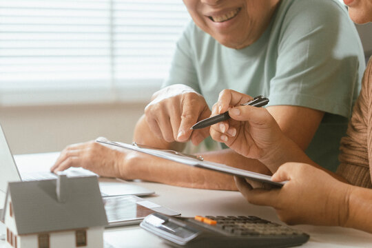 senior couple and documents with laptop for finance, budget planning or retirement annuity on sofa. Elderly man, woman or house with smile, computer or paperwork for pension fund or insurance