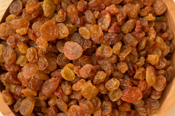 Dried brown golden raisins close-up top view. Texture of scattered organic raisins, macro photography. Sweet tasty dried fruit, dried grapes. Ingredient for cooking, baking desserts