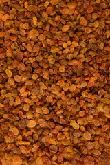 Dried brown golden raisins close-up top view. Texture of scattered organic raisins, macro photography. Sweet tasty dried fruit, dried grapes. Ingredient for cooking, baking desserts