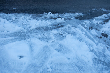 quiet, snow-covered road winds winter landscape, pavement after heavy snowfall, Slippery surface warning, wet snow melts, Cold morning drive, icy snow patches on paved road, hazardous driving surfaces