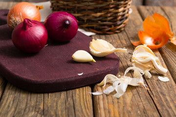 onions and garlics on cutting board, weathered wooden background
