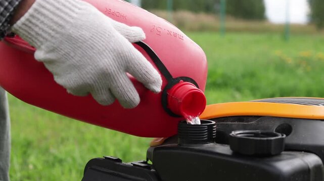 Refueling a lawnmower with gasoline from a can.