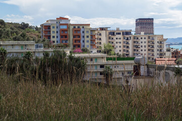 Fototapeta premium Golem, Albania: Residential buildings meet the vibrant Adriatic Sea and sandy beach. This popular coastal town blends modern and traditional architecture.