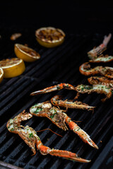 Virgin lobster and lemon on hot BBQ gas grill searing with fire visible under the grill