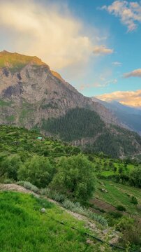 4K Vertical shot of Orange clouds above the Himalayan mountain range during the sunset after rain in monsoon season as seen from Killar town in Chamba district, Himachal Pradesh, India. Scenic sunset.