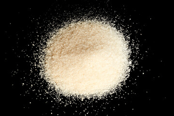 Granulated sugar crystals forming a circular mound isolated on black background
