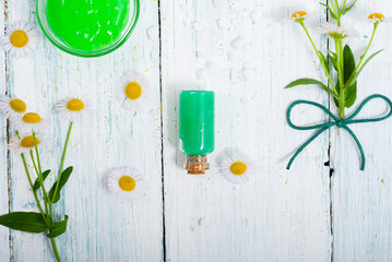 beauty product samples with chamomile flowers on white wooden table