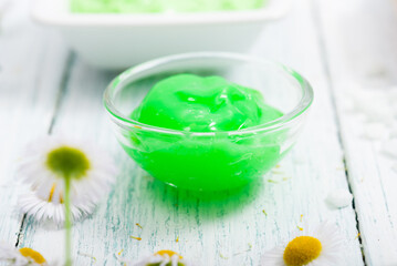 beauty product samples with chamomile flowers on white wooden table