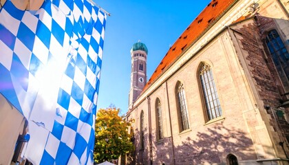 Fototapeta premium Blue and white Oktoberfest banner waving outdoors with Munich’s landmark Frauenkirche cathedral in the background