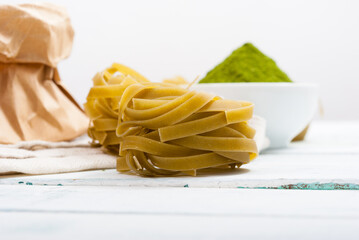 uncooked taglatelle pasta and ingredients: grounded spinach powder and whole wheat flour