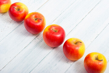 apple fruits in a row, white wooden table background