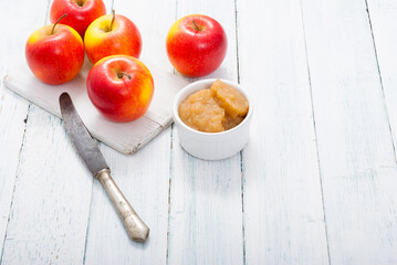 apple jam at porcelain dish, apples, cinnamon, white wood table background