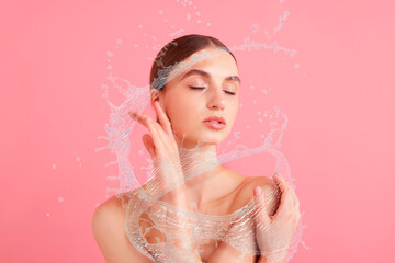 Young woman with smooth skin and water splashes on pink background