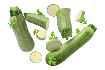 Pieces of fresh zucchinis and parsley falling on white background