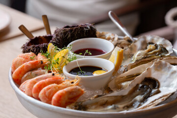 Seafood (oysters, shrimps, sea-urchins, mussels) are decoratively put on ice in a big plate
