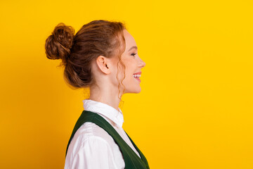 Side profile of a young female student with a bright smile against a vibrant yellow background...