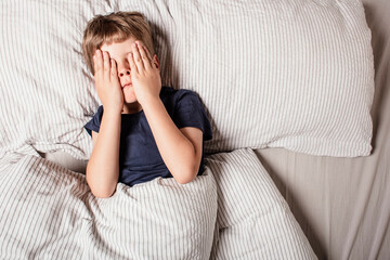 The child was scared before going to bed. Night terrors in a child. The kid covers his face with...