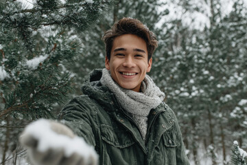 young man playfully throws snowball towards camera in snowy forest setting