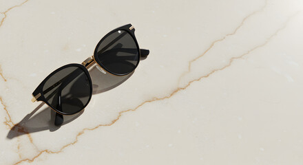 Elegant black sunglasses with golden accents displayed on a veined marble surface catching sunlight capturing