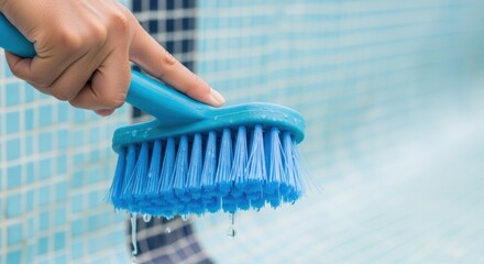 Hand cleaning swimming pool tiles with blue brush