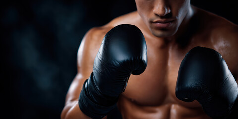 Boxer wearing black boxing gloves preparing for fight on dark background
