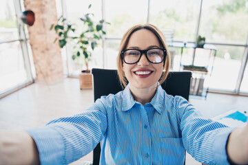 Confident young businesswoman in stylish office interior smiling and enjoying workday in corporate...