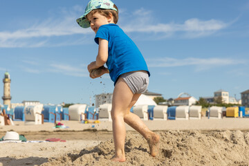 Junge spielt an der Ostsee in Warnemünde mit Sand und Wellen