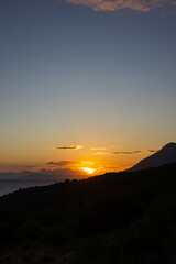 Obraz premium Sunset over the Adriatic Sea with a view of the mountain slope and the coast. Podaca village, Makarska Riviera, South Dalmatia, Croatia.