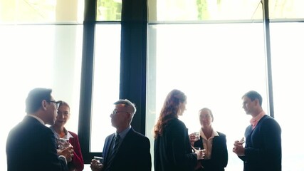 Silhouetted professionals network at corporate conference reception, chatting near large windows. Business gathering blends seminar, meetup, and event vibes for productive connections.