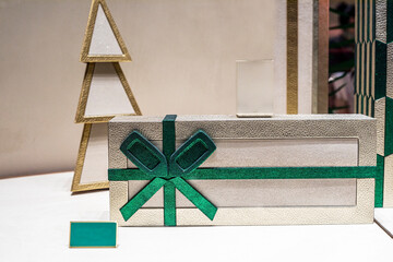 stylish new year gift tied with a green ribbon with a decorative christmas tree in the background....
