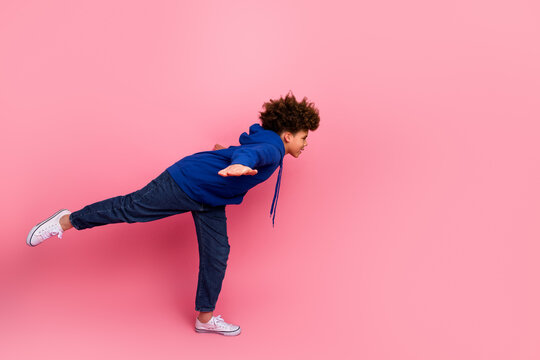 Joyful boy balancing on one foot against a vibrant pink backdrop showcasing vibrant apparel in a cheerful and lively pose - Powered by Adobe