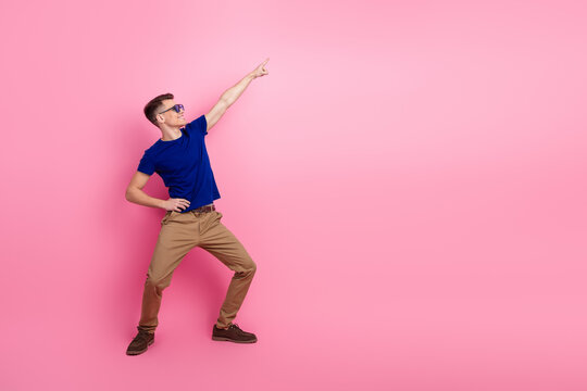 Stylish young man in casual attire making a fun pose with gesture against a vibrant pink background, promoting fashion