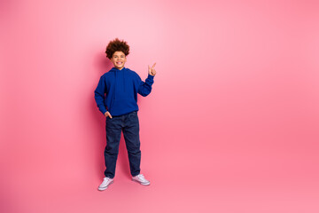 Happy boy in blue hoodie posing confidently with a modern casual look on a vibrant pink background