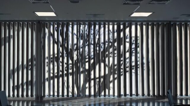 Non-literal artistic pattern of arboreal shade projections onto expansive pane with slatted window coverings