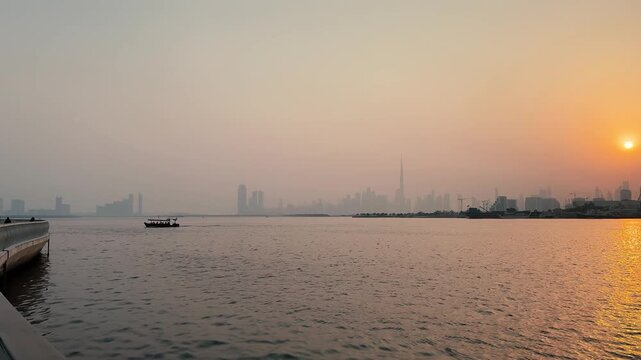 Scenic video of a boat sailing in Dubai creek at sunrise with faded Dubai downtown skyline in the background 